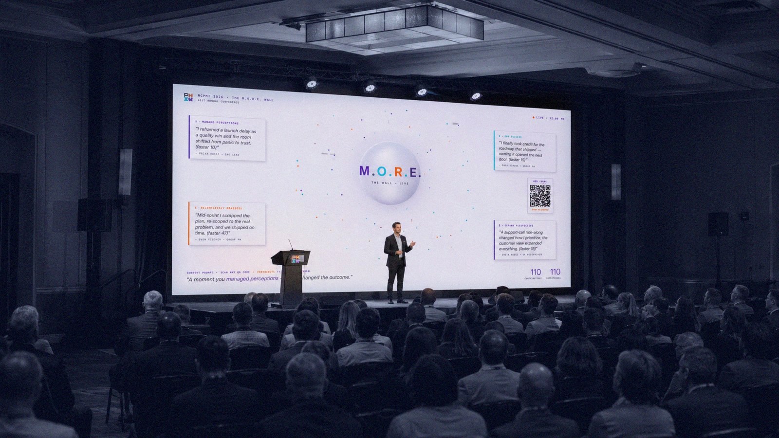 The M.O.R.E. Wall live on the main screen at a 400-person conference, audience seated